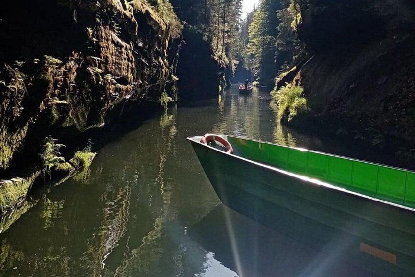 A narrow river with a green boat and a person in a canoe. 2