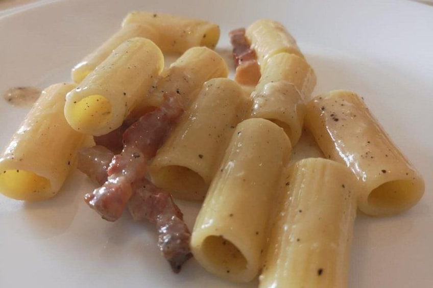 A plate of rigatoni pasta with cheese and bacon. 5