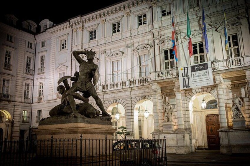 A statue in front of a historic building with flags. 1