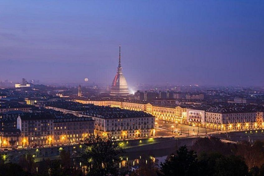 A cityscape at dusk with illuminated buildings and a prominent tower. 2