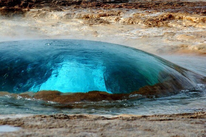 A large, clear blue water body surrounded by rocky terrain. 5
