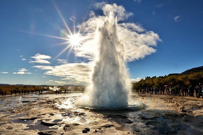 A geyser erupting with a crowd watching, under a clear sky. 3