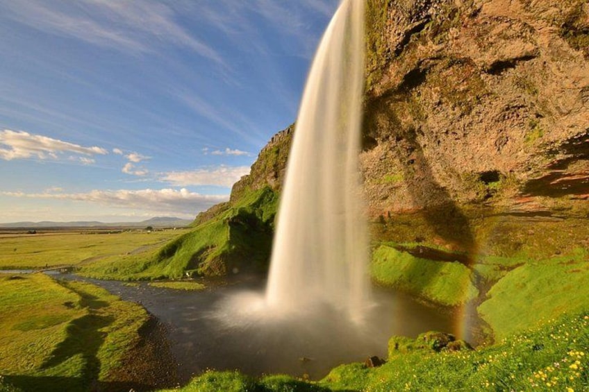 A waterfall cascading down a cliff into a green valley. 4