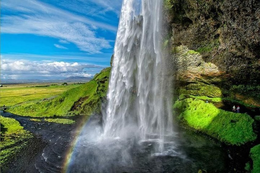 A waterfall cascading down a cliff, surrounded by lush green fields and a clear blue sky. 5