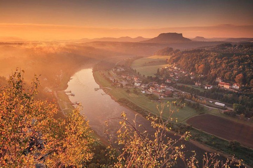 A river winding through a valley with a town on the right bank, surrounded by fields and hills. 1