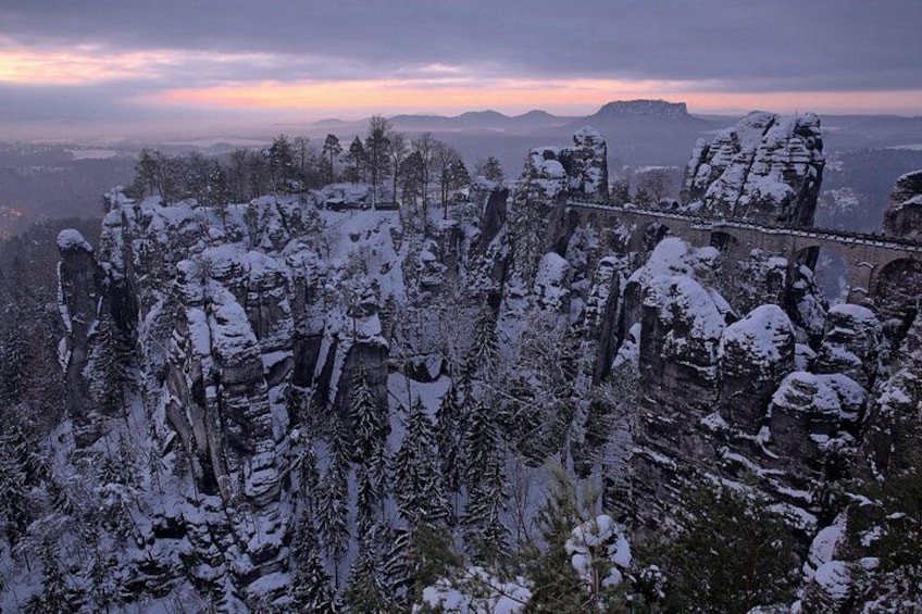 A snow-covered mountainous landscape with rock formations and trees. 5