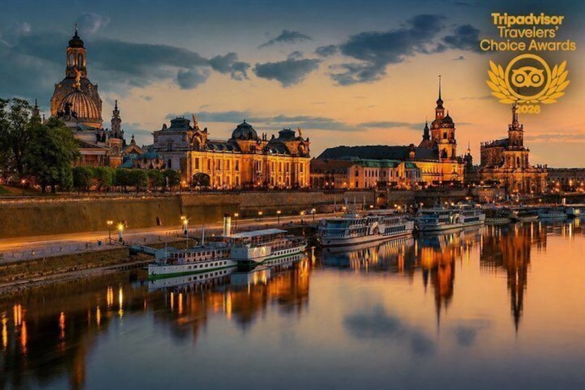 A river with boats, historic buildings, and a city skyline at dusk. 1