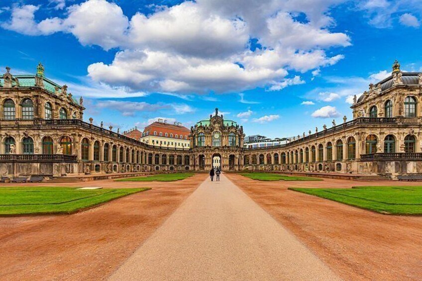 A grand palace with symmetrical architecture, a central courtyard, and a clear sky. 2