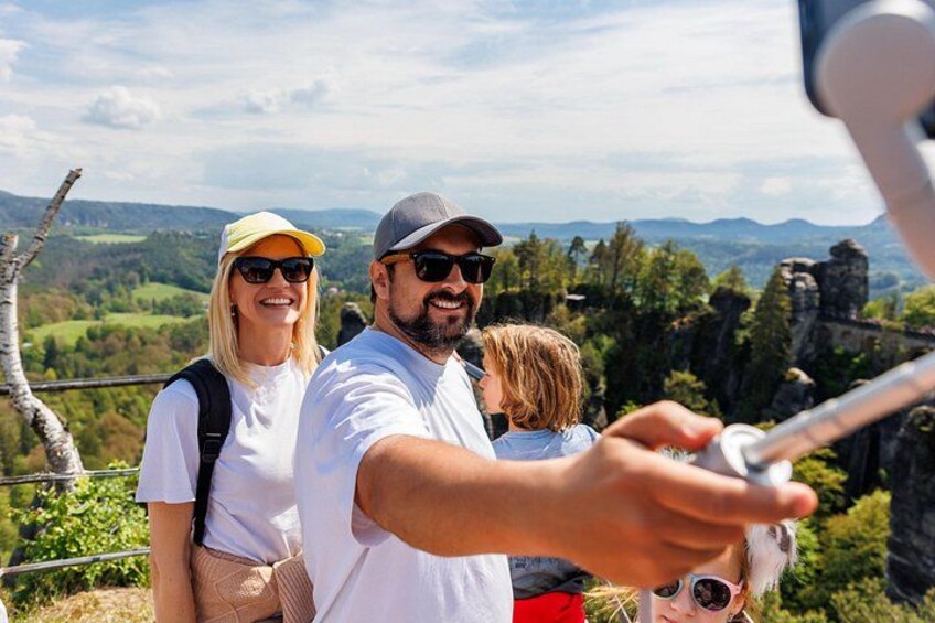 A family taking a selfie with a scenic landscape in the background. 2