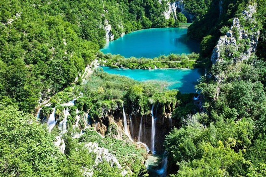 Une cascade se jetant dans un lac turquoise, entouré d’une forêt dense. 1