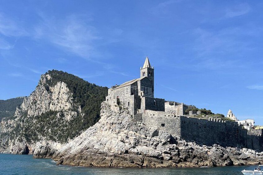 Una fortaleza costera con una torre destacada, acantilados rocosos y un cielo azul despejado. 4