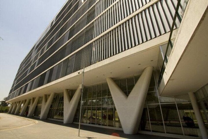 Un edificio moderno con un diseño arquitectónico único, que presenta una serie de listones verticales y una estructura de soporte triangular distintiva. 1