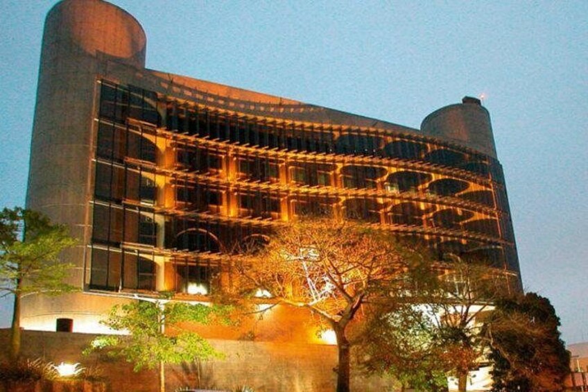 Un edificio moderno con una torre cilíndrica y una fachada con un patrón de ventanas en forma de cuadrícula. 5