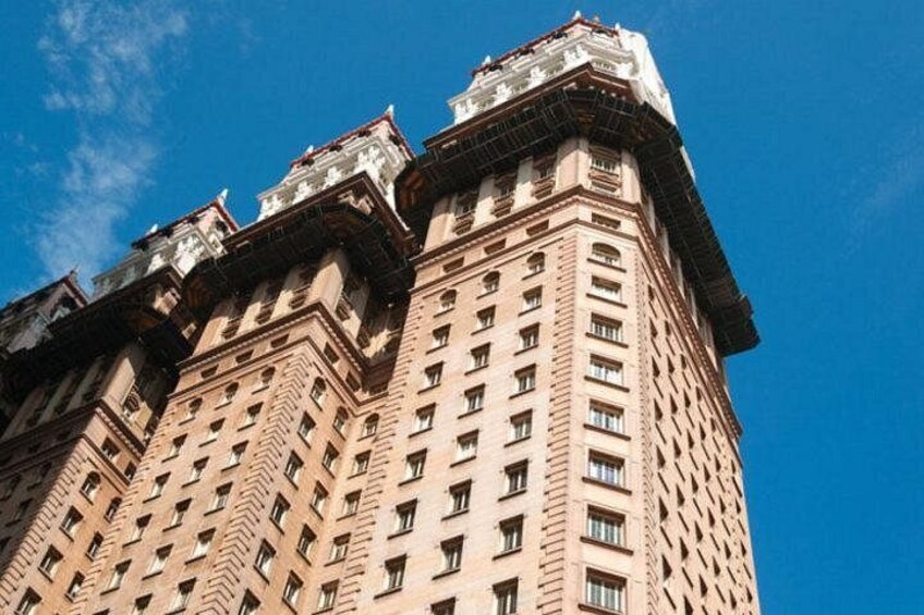 Un edificio alto de varios pisos con un estilo arquitectónico distintivo, que presenta una serie de secciones salientes y un cielo despejado al fondo. 4