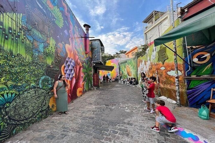Un mural colorido en una pared de calle, un sendero de adoquines y un edificio con toldo verde. 5