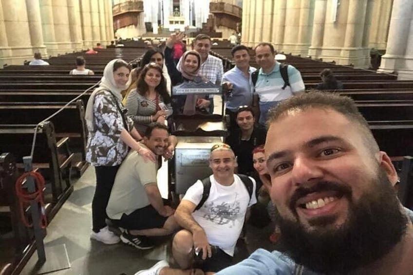 A group of people inside a large, historic building with high ceilings and rows of seating. 5