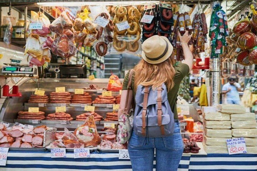 A person browsing a market with various meats and sausages on display. 3
