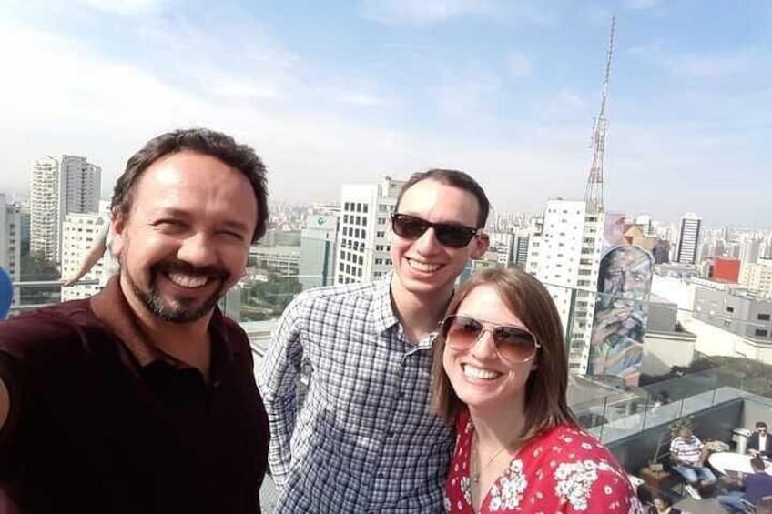 Three people posing with a cityscape in the background. 4