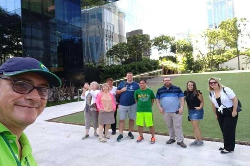 A group of people standing on a paved area with a modern building in the background. 2