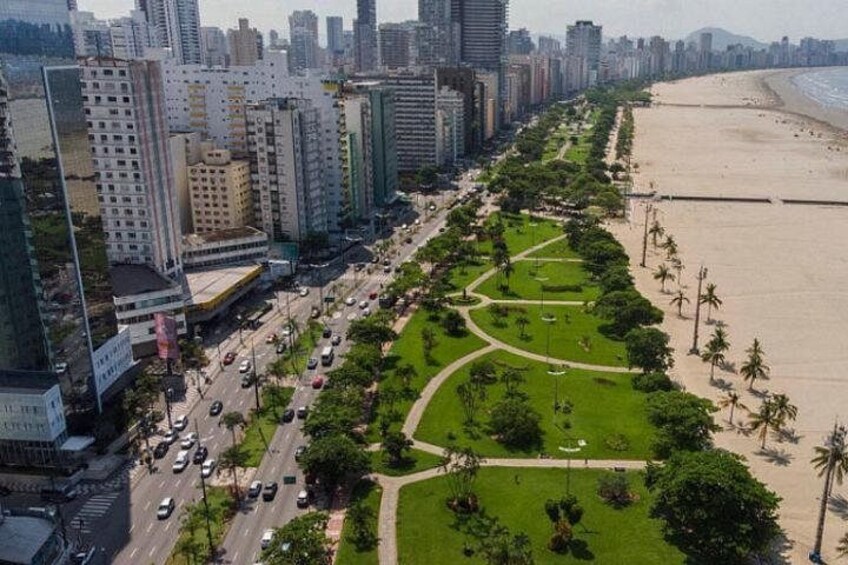 Een kuststadsgezicht met een brede weg, groene parken en een strand. 5