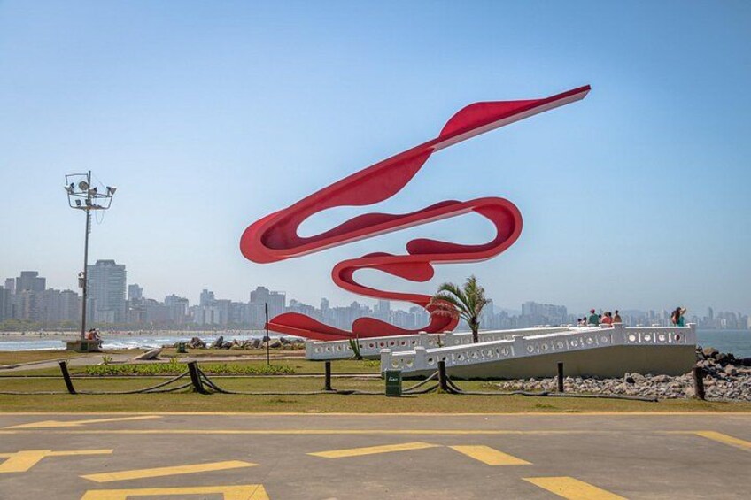 A red sculpture on a waterfront with a city skyline in the background. 1