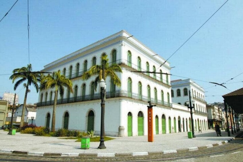 A white building with green accents and arched windows, surrounded by palm trees and a clear sky. 4