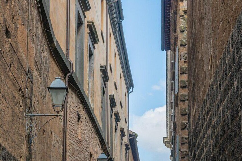 A narrow street with old buildings, a street lamp, and a clear sky. 2