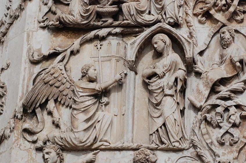 A detailed stone carving with an angel and a figure holding a cross. 4