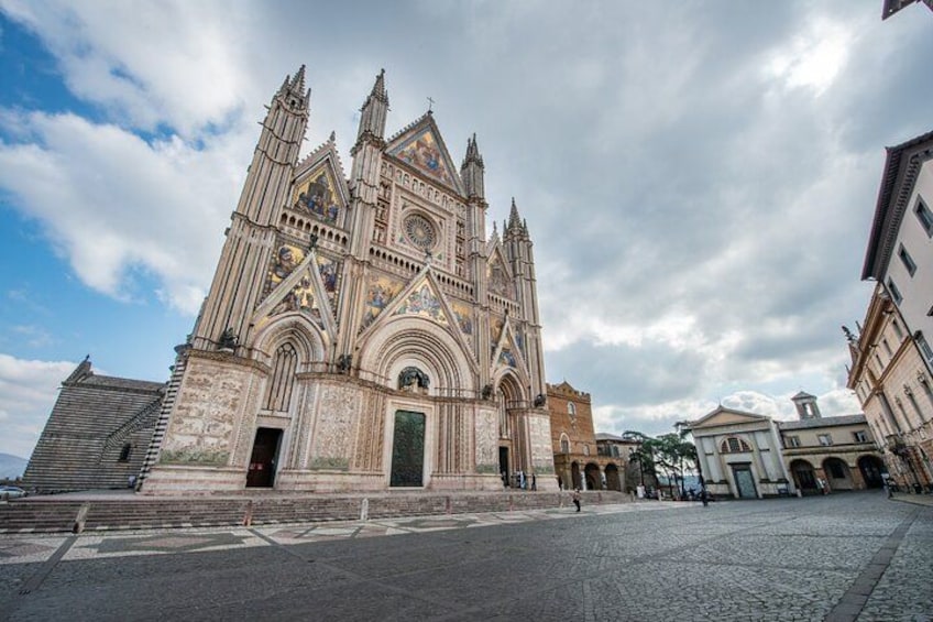 A large cathedral with intricate architecture, a cobblestone street, and a clear sky. 1