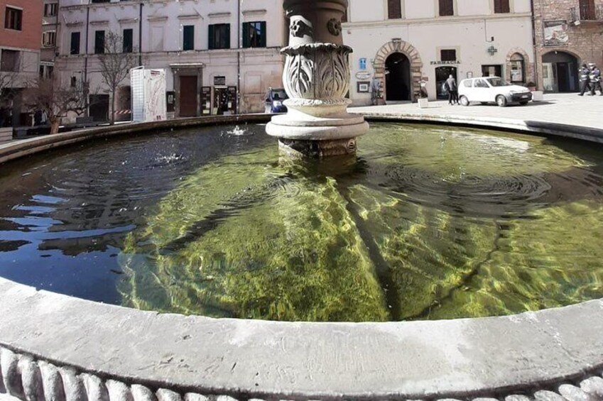 A fountain with a statue in the center, surrounded by a stone border. 2