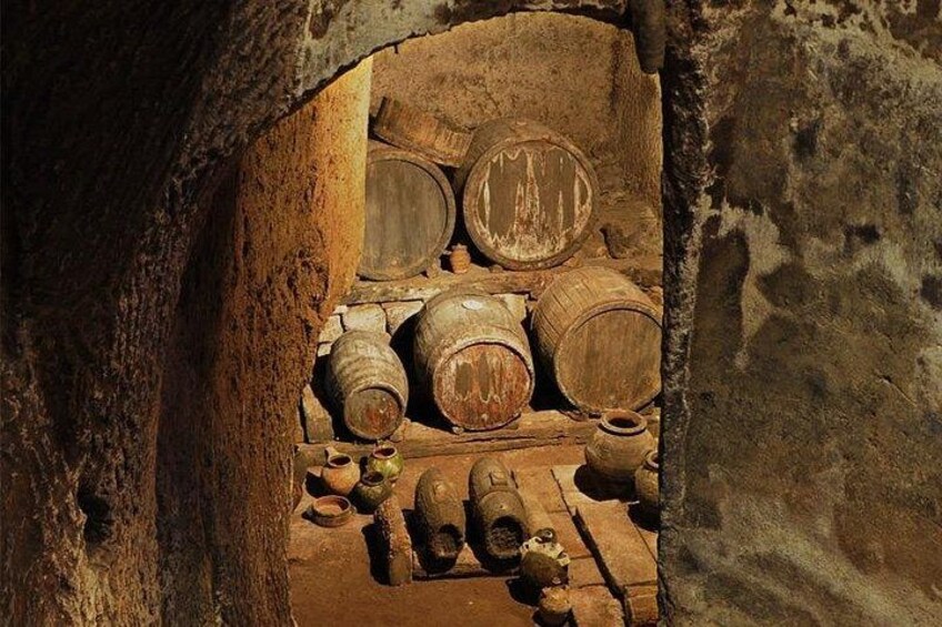 Un antiguo arco de piedra con barriles de madera y cerámica en su interior. 2