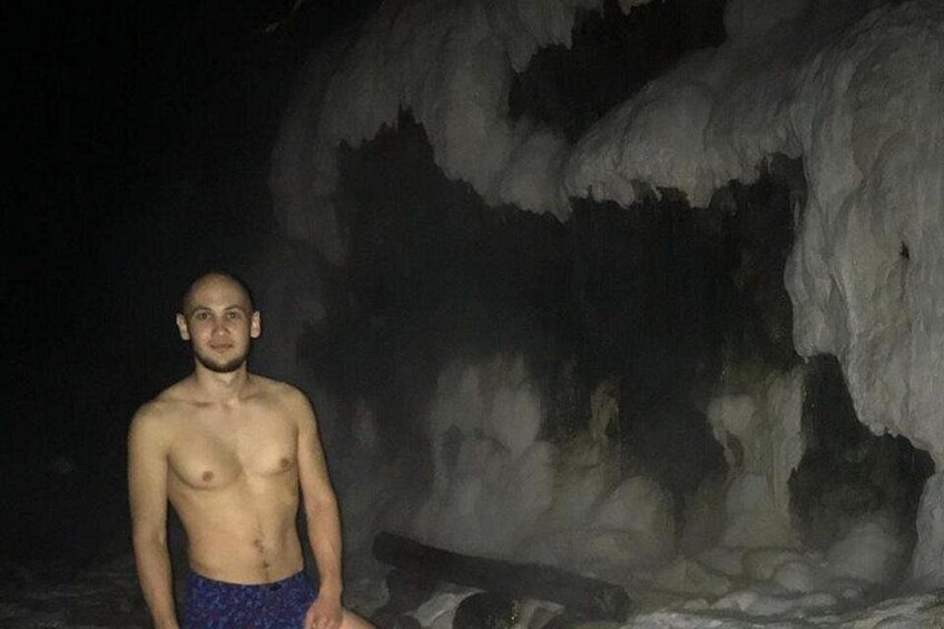 Eine Person steht vor einer Höhle mit Eisformationen. 5