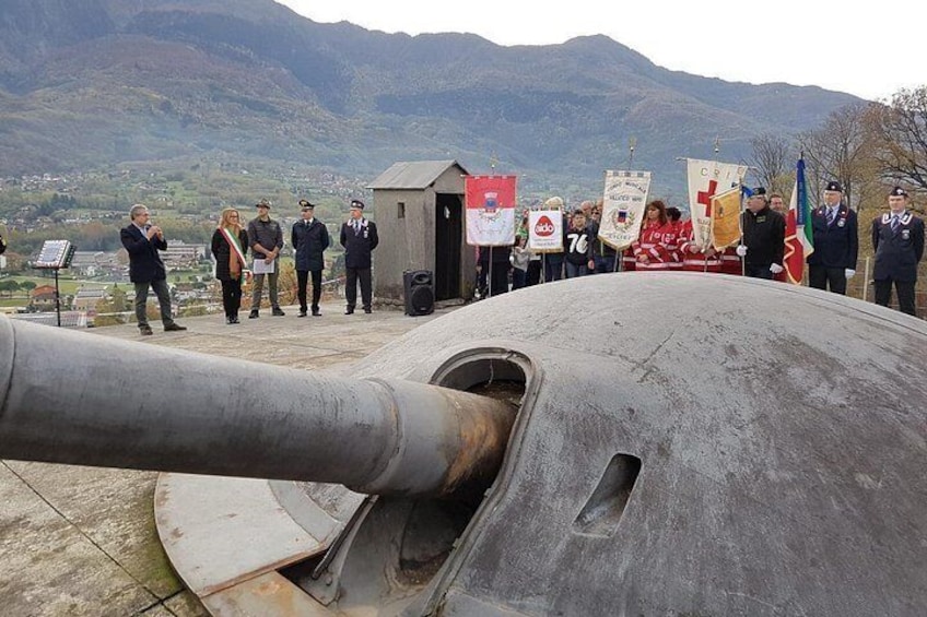 Un grupo de personas de pie frente a un gran cañón con banderas y estandartes. 4