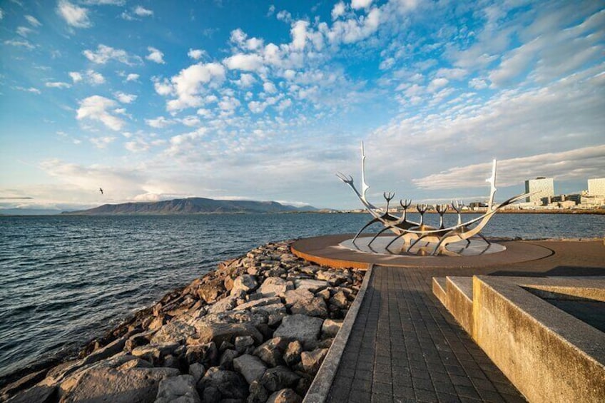 A rocky shoreline with a metal sculpture and a paved walkway. 4