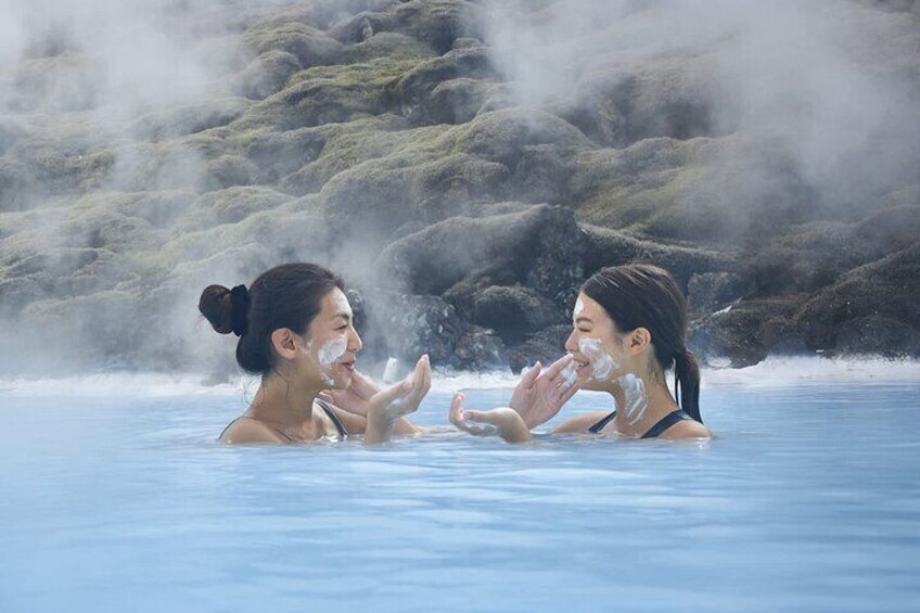 Two people in a geothermal spa with steam rising from the rocks. 2