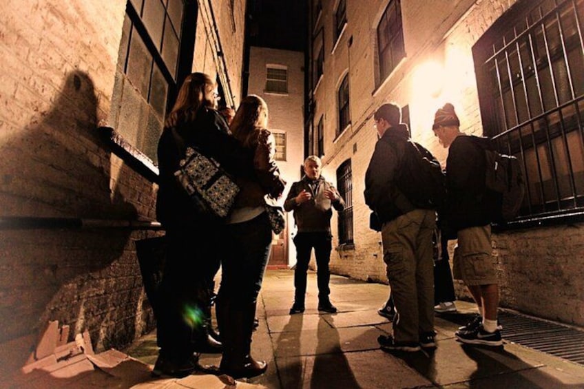 Un groupe de personnes se tient dans une ruelle, la nuit. 1