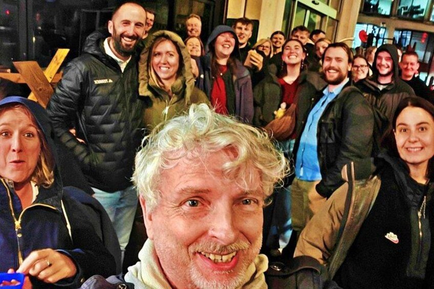 Un grupo de personas reunidas en un espacio interior, algunas con chaquetas, lo que sugiere un ambiente fresco o frío. 4