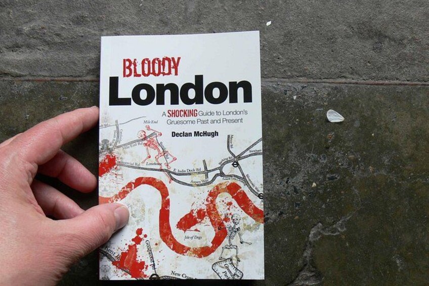 Una mano sosteniendo un libro titulado 'Bloody London' de Declan McHugh. 2
