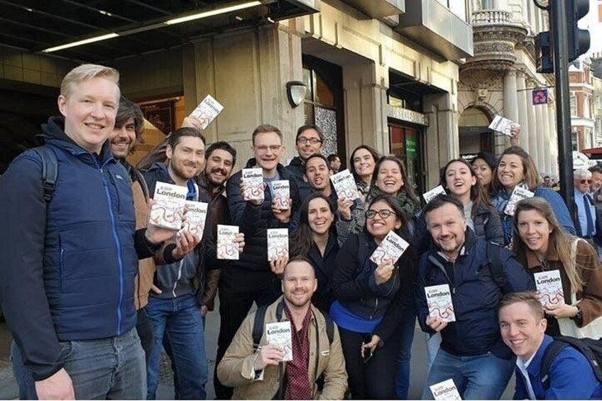 Un grupo de personas sosteniendo libros con el título 'London' en un entorno urbano con detalles arquitectónicos. 3