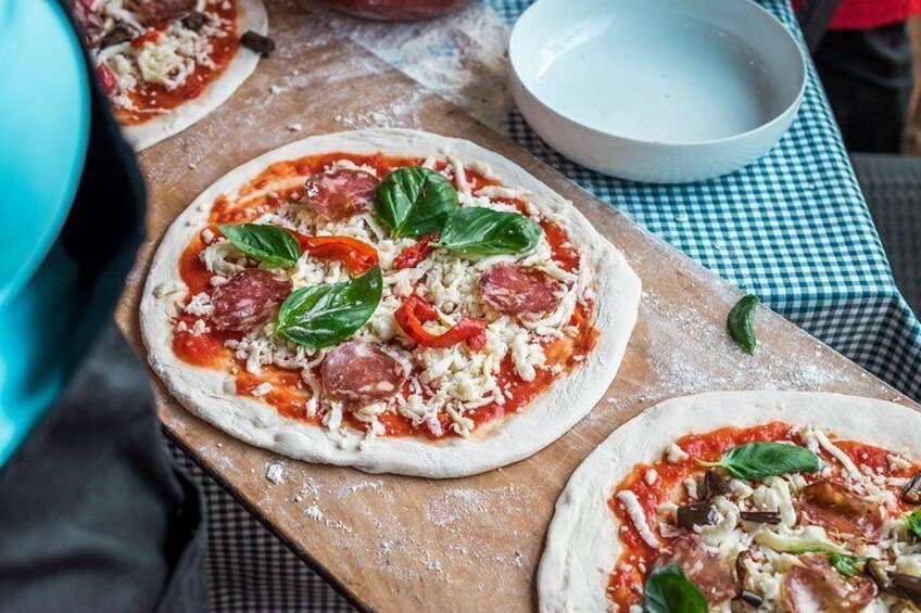 Tres masas de pizza con ingredientes sobre una tabla de madera. 1