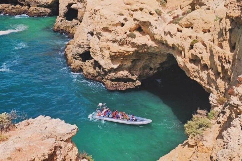 A boat with passengers navigating through a rocky coastal area with clear blue waters. 3