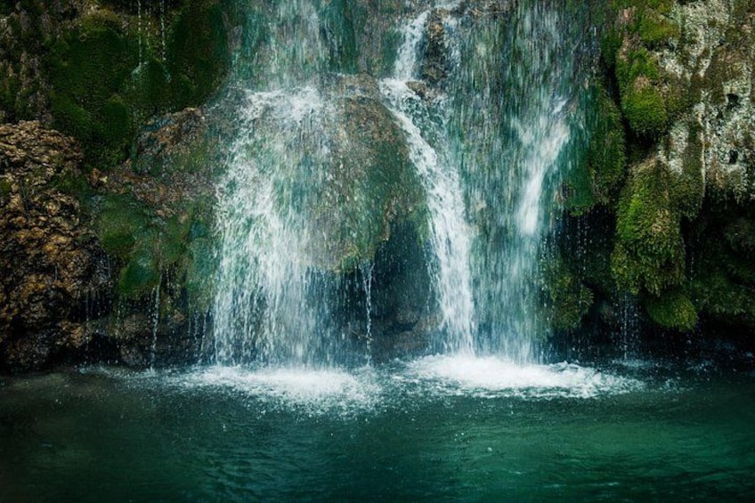 A waterfall cascading over moss-covered rocks into a body of water. 2