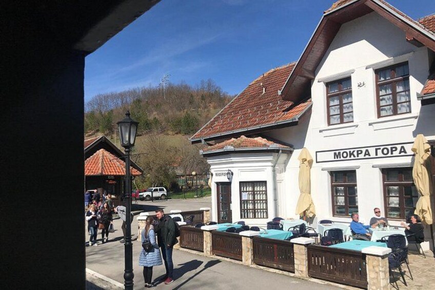 A building with a sign reading 'MOKRA GORA' and outdoor seating. 1