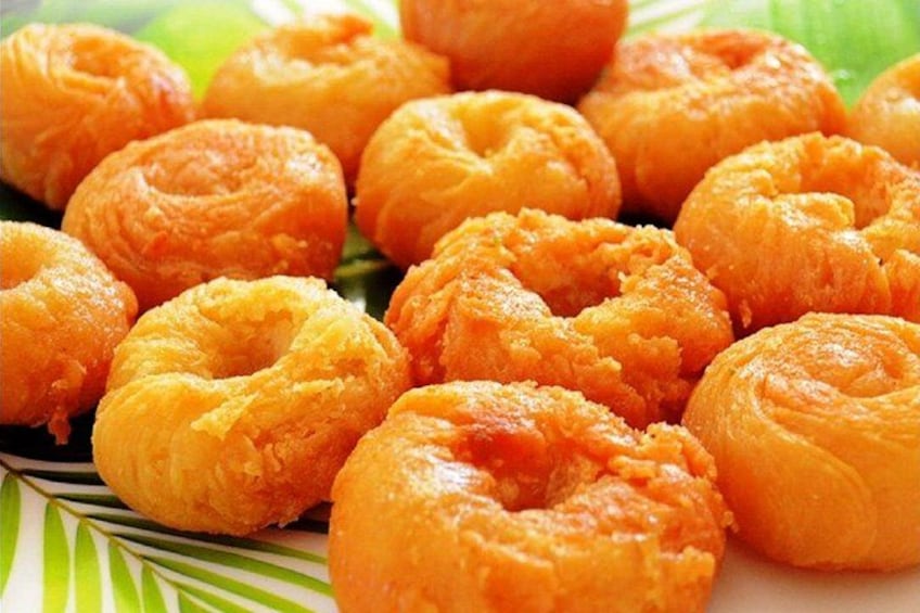 Een bord met glanzend bruine gebakjes, gerangschikt op een bord met een groen patroon. 1