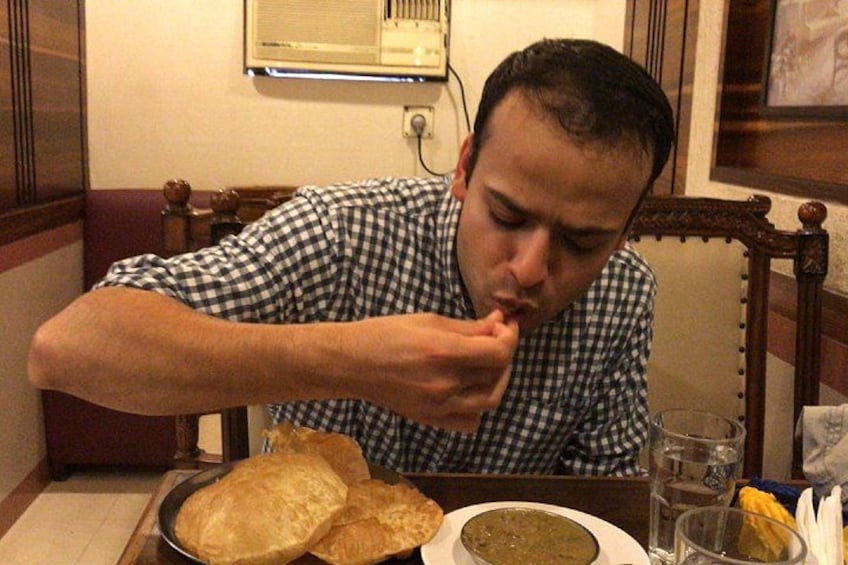 Iemand zit aan een tafel met een bord eten, een glas water en een kom soep. 2