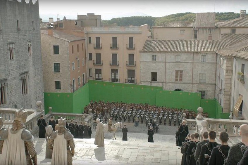 A group of people in historical costumes gathered in an outdoor setting with buildings in the background. 3