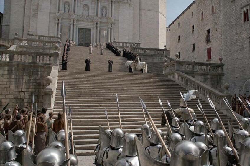 Un bâtiment historique doté d’un magnifique escalier, où l’on peut voir des soldats en armure et une foule de personnes. 1