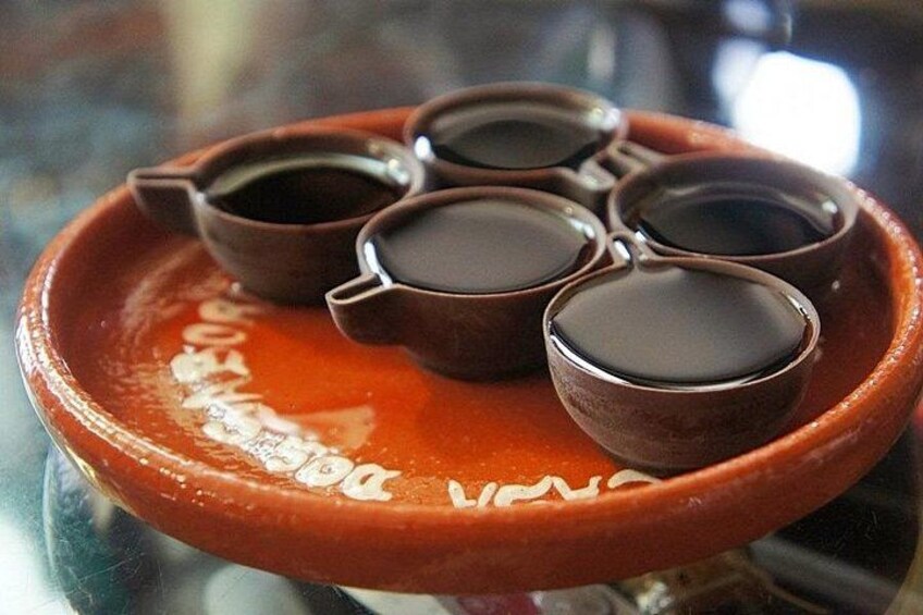 Un tajine marocain traditionnel, servi dans une assiette en argile rouge, accompagné de quatre petits bols de sauce. 2