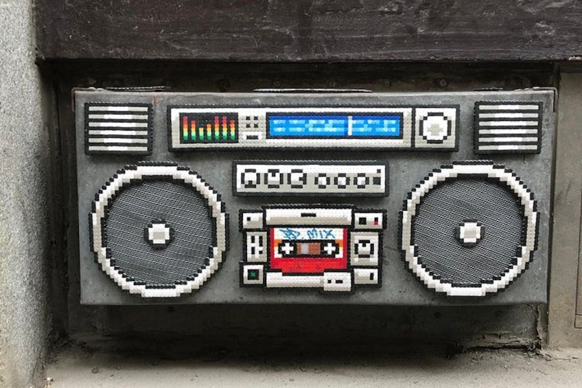Un reproductor de música pixelado con dos altavoces grandes, una pantalla central y varios botones. 5
