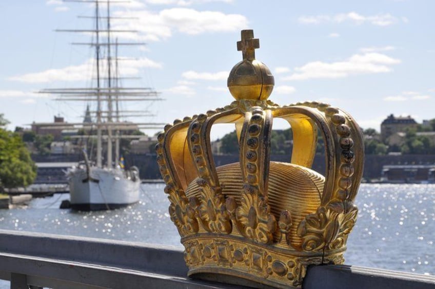 A golden crown with intricate designs, a ship in the background, and a body of water. 2